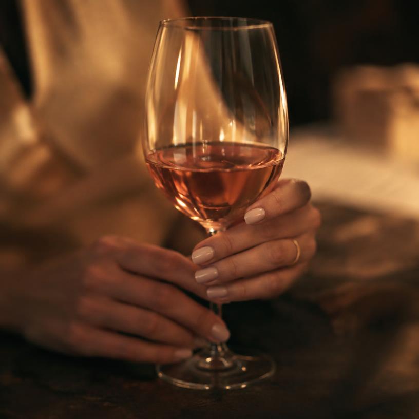Hands holding a glass of rosé in warm light